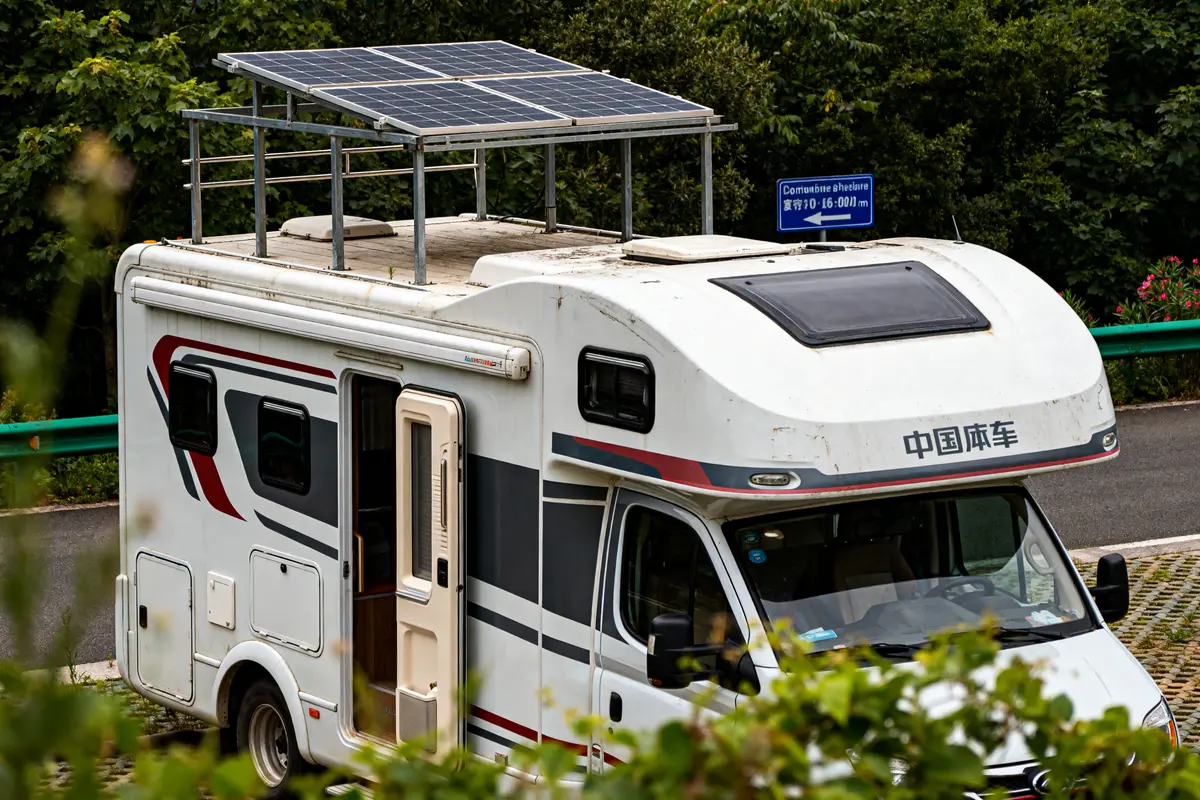 Camping car chinois équipé de panneaux solaires garé sur une aire verdoyante