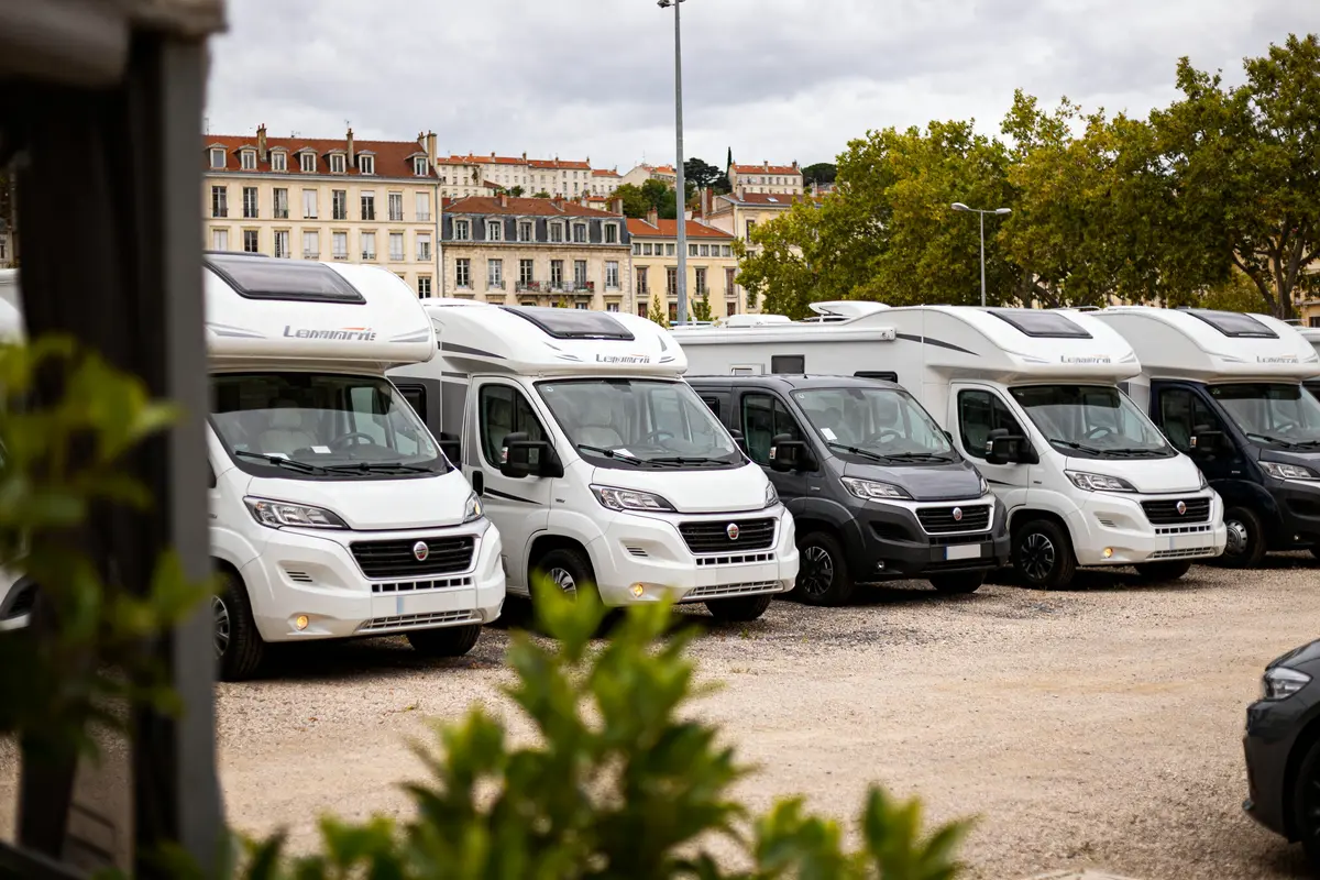 Alignement de camping-cars stationnés à Lyon avec bâtiments historiques en arrière-plan