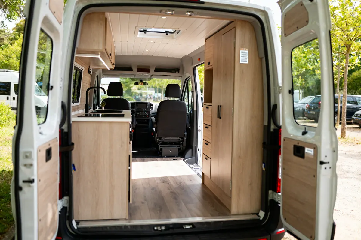 Intérieur aménagé d'un panama van avec cuisine en bois et sièges avant visibles