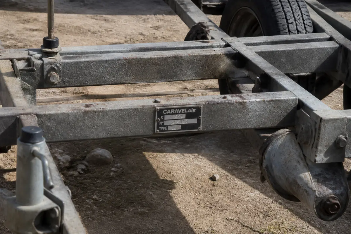 Châssis rouille de remorque Caravelair avec plaque d'identification visible, fond terreux.