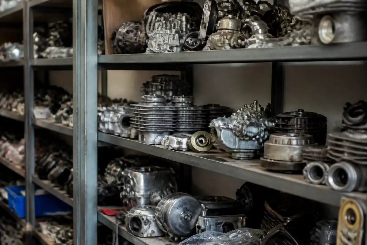 Étagères métalliques remplies de pièces mécaniques variées empilées dans un entrepôt de stockage.