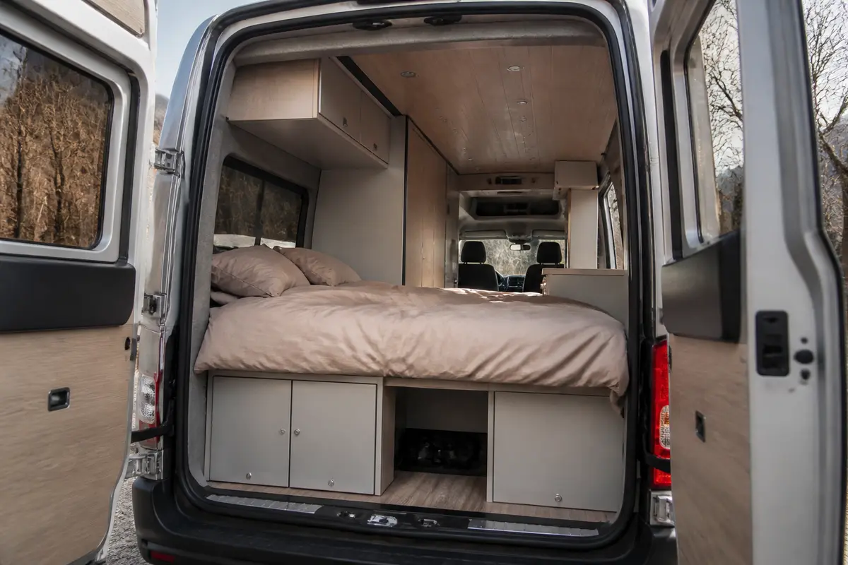 Intérieur spacieux d'un van aménagé avec un lit permanent et rangement intégré
